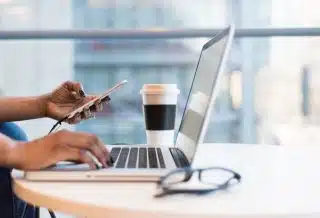 person using smartphone and MacBook